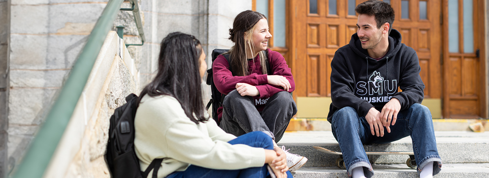 Three students sitting and chatting an a set of stairs.